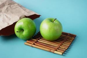 manzana de color verde y bolsa de papel en la mesa foto