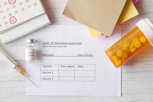 vaccination record card , hand sanitizer and mask on color background photo