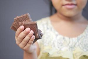 child girl hand pick dark chocolate against gray background photo