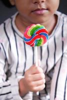 child girl holding a rainbow shape lollipop photo