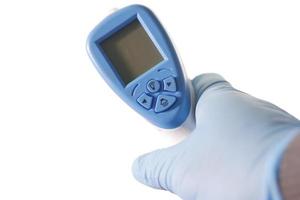 mano que sostiene el termómetro infrarrojo para medir la temperatura.