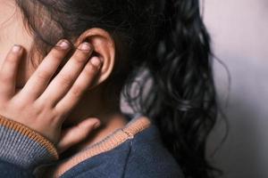 child girl having ear pain touching his painful ear , photo