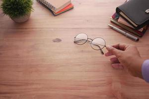 rear view of man hand holding old eyeglass on table photo