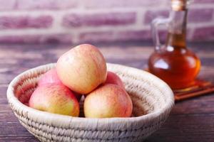 Vinagre de manzana en botella de vidrio con manzana verde fresca en la mesa foto