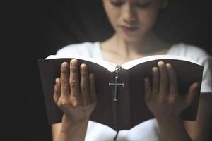 las escrituras y la cruz están siendo leídas por una joven honesta y cristiana para orar ideas, creer, fe, orar, desear. foto