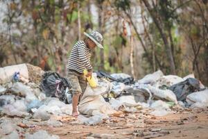 A poor boy collects trash from a landfill in the suburbs. Life and way of life of the poor Concept of child labor, poverty, environment. Waste separation. photo