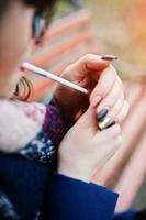 Young girl lighting cigarette outdoors close up. Concept of nicotine addiction by teenagers. photo