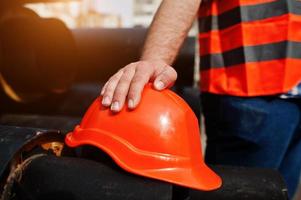 Hand of worker man in safety orange helmet near steel pipes. photo