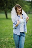 Portrait of brunette girl on checkered shirt, jeans and veil at hen party.
