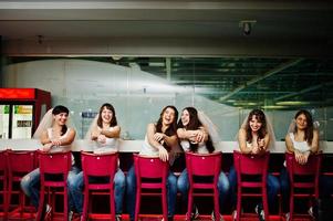 Six girls on veil sit at the bar stools on hen party. photo
