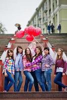 grupo de seis chicas divirtiéndose en la despedida de soltera, con globos bajo la lluvia en las escaleras de la ciudad. foto
