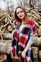 Young hipster girl wear on blanket against wooden stumps on wood. photo