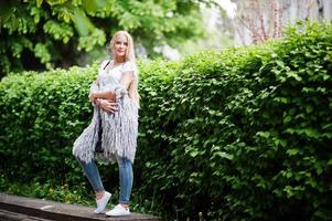 Stylish blonde woman wear at jeans and girl sleeveless with white shirt against bushes at street. Fashion urban model portrait. photo