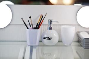 Make up brushes with bottle of water at beauty salon. photo