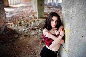 Portrait girl with red lips wearing a red checkered shirt with bare shoulders posed sexy background abadoned place. photo