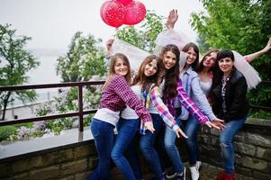 Group of six girls having fun at hen party, with balloons under rain. photo