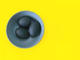 Black eggs on the yellow background. Easter, diversity, geometric, food concept photo