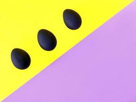 Black eggs on the yellow and violet background. Easter, diversity, geometric, pattern, food concept photo