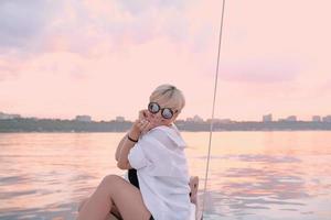 Beautiful blonde happy woman enjoying sunset on the yacht in the sea. Travel, adventure, relaxation concept photo