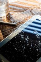 agua derramada sobre la tableta, gotas de agua en la pantalla de la tableta