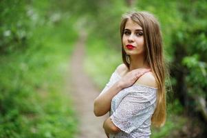 Portrait of beautiful girl with red lips at spring blossom garden, wear on red dress and white blouse. photo