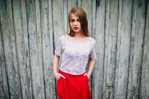 Portrait of beautiful girl with red lips against wooden background, wear on red dress and white blouse. photo