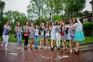 Eleven attractive braidsmaids with lovely bride celebrating bachelorette party with champagne in the park. photo