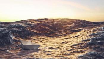 puesta de sol con barco de papel luchando contra la ola en el océano, liderazgo y concepto de negocio foto