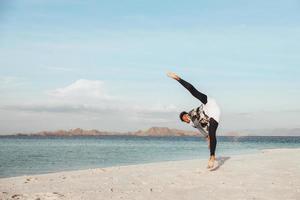 A guy training taekwondo kick martial art on the beach photo