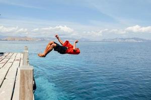 un hombre haciendo backflip en el agua de mar foto