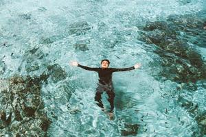 hombre asiático en traje de neopreno nadando en el mar transparente foto
