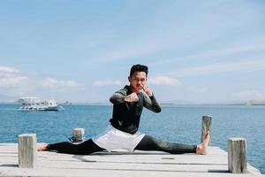 Taekwondo guy sitting with split legs style with sea background photo