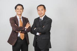 Two Asian businessman in suit and tie posing together with confident with arms crossed photo