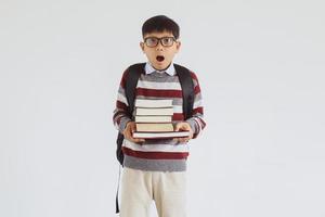 Shocked Asian student looking to the camera while holding stack of book photo