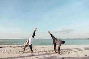 dos hombres entrenan capoeira arte marcial en la playa foto