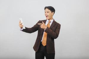 Happy asian businessman in suit and tie get surprise while pointing finger to the smart phone photo