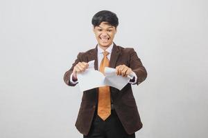 hombre de negocios asiático enojado con traje y corbata que parece molesto y rasga papel foto