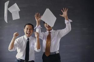 Blurred photo of two excited Asian businessmen and throwing sheets of paper