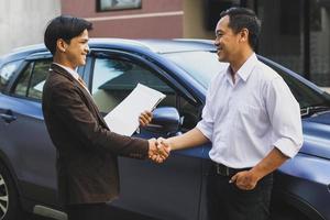 Seller and customer who bought a car shaking hands photo