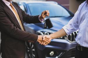 Hand giving a car key with handshake for car transaction deal concept photo
