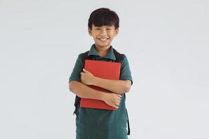 Smiling Asian school boy carrying a book