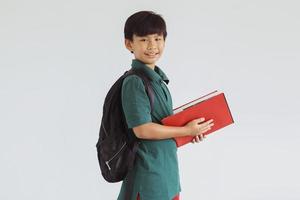 estudiante asiático sonriente mirando a la cámara mientras sostiene un libro foto