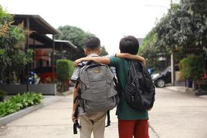 Back view of two students embrace each other going to school photo