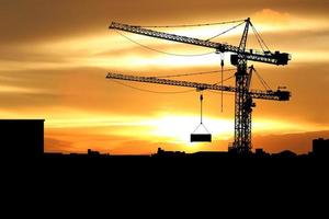 Silhouette of Tower crane on a construction site on sunset background. photo