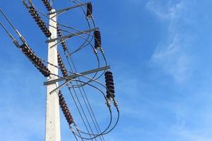 High voltage electrical insulator hanging on electric pole with blue sky background. photo