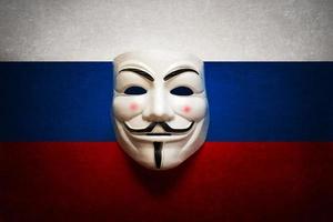 máscara de hacker en una pantalla de computadora con el fondo de la bandera rusa