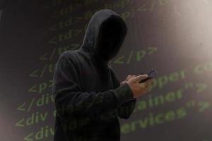 Computer hacker in mask and hoodie over abstract Data thief background. photo