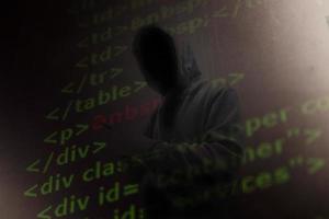 Computer hacker in mask and hoodie over abstract Data thief background. photo
