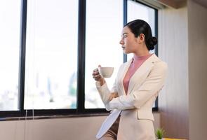 empresaria tomar un descanso beber café oficina con luz de ventana. foto