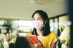 Adult asian woman wear mask protect virus corona using mobile phone for app music photo